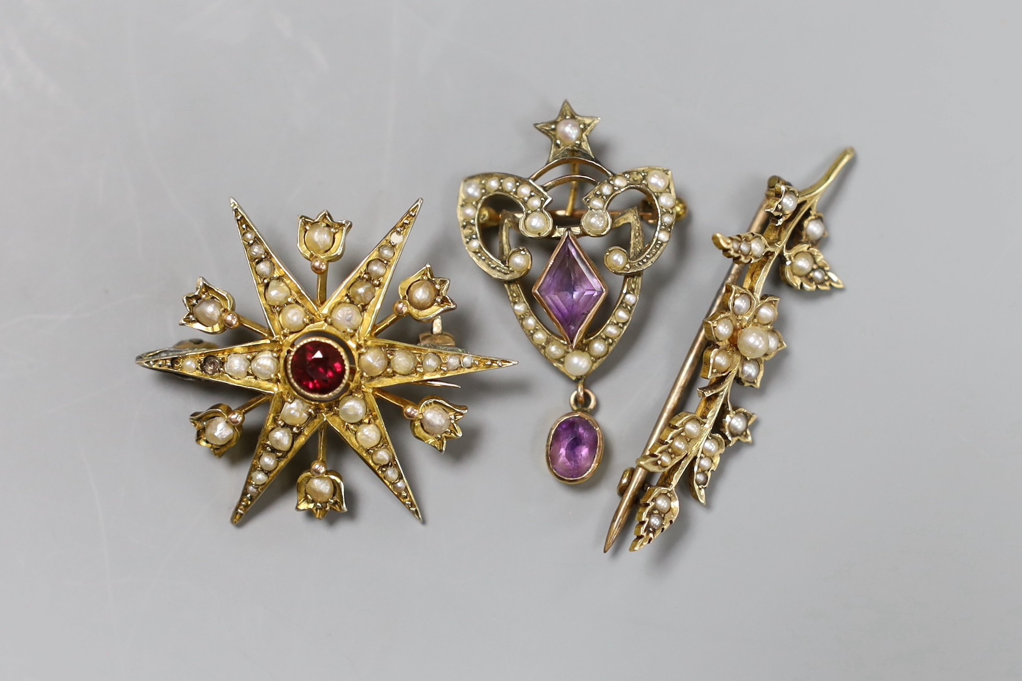 An Edwardian 9ct gold seed pearl and simulated ruby starburst brooch, 3.25cm, a pearl set bar brooch and an amethyst set drop brooch, gross 11.3 grams